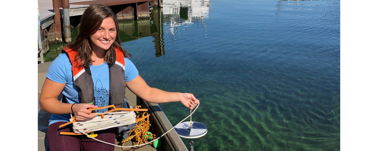 Jasmine Mancuso holds a secchi disk over a Muskegon Lake cyanobacterial bloom